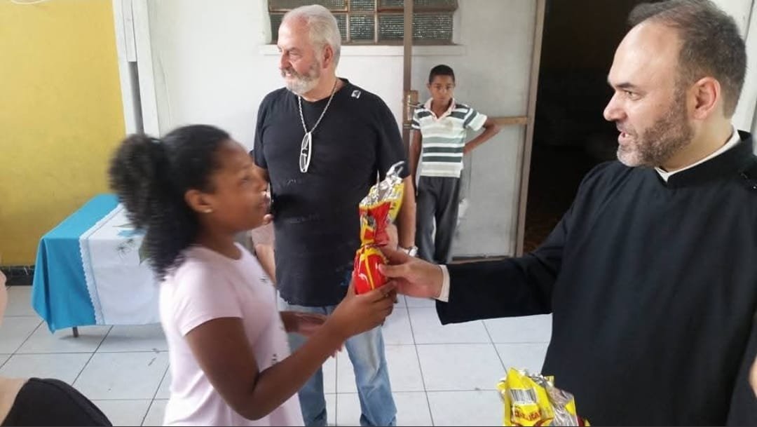 Sacerdote entrega presente a uma menina