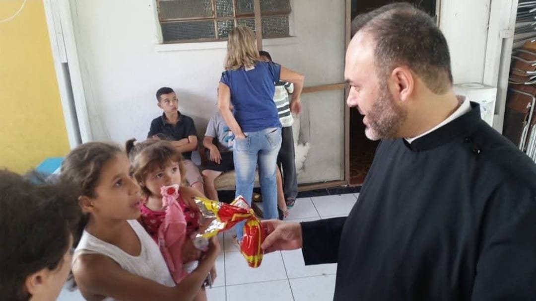 Criança recebe presente do sacerdote