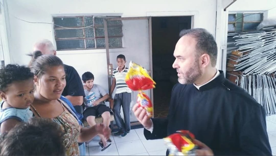 Sacerdote entrega presente a uma família