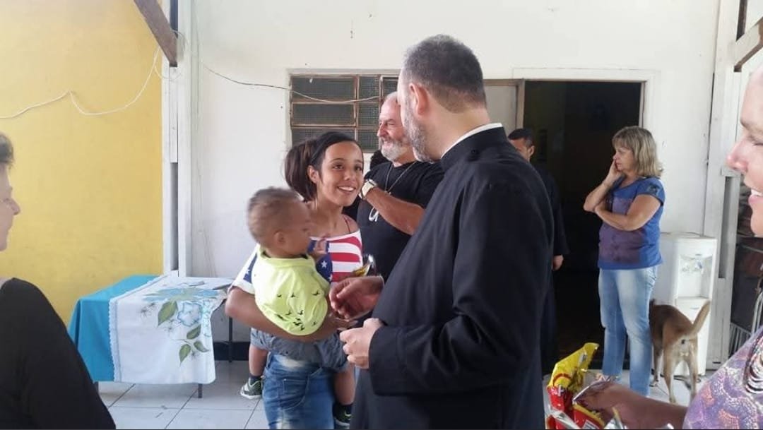 Sacerdote com uma família durante a entrega