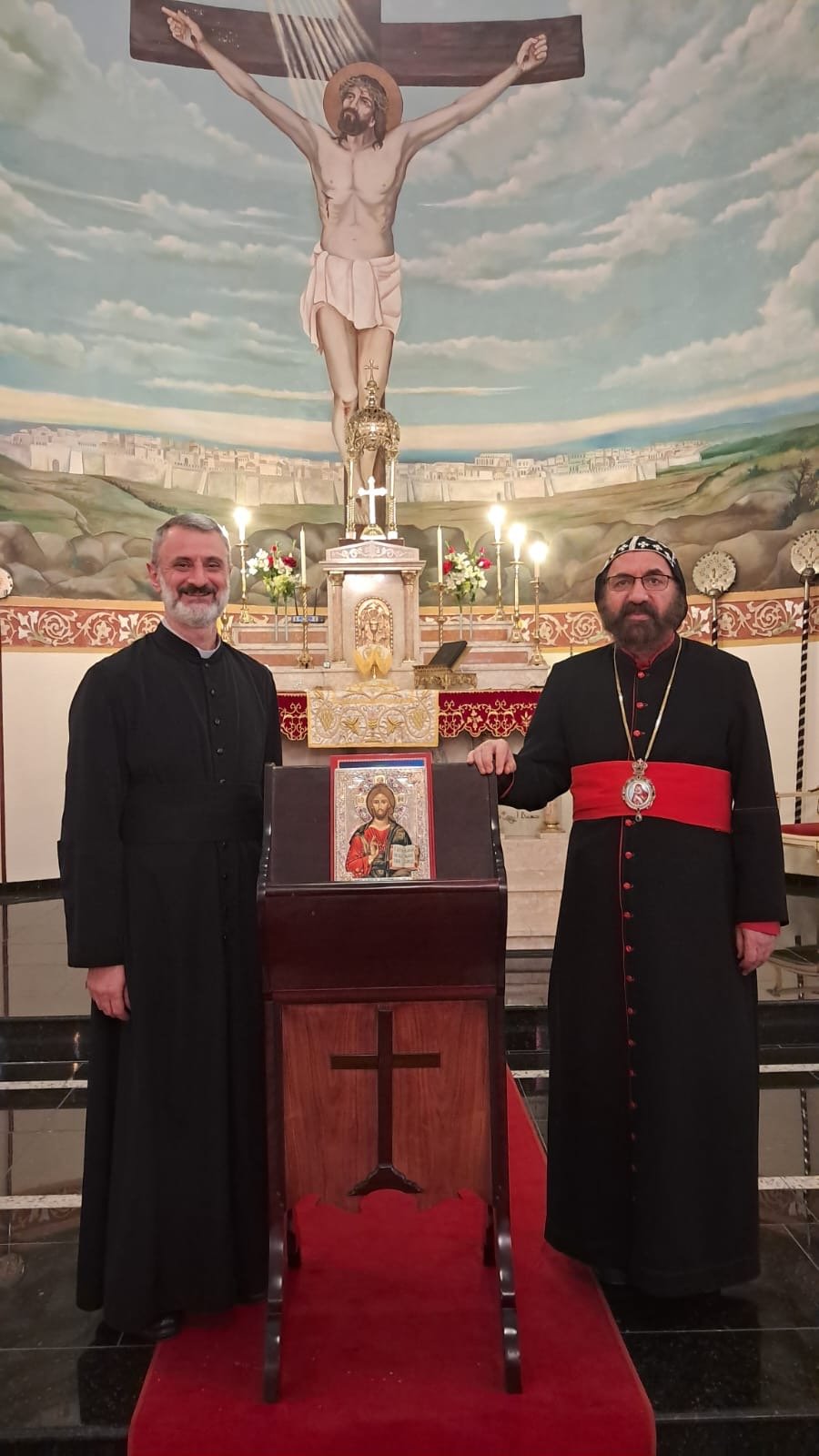 Clero da paróquia junto ao ícone, diante do mural da crucificação