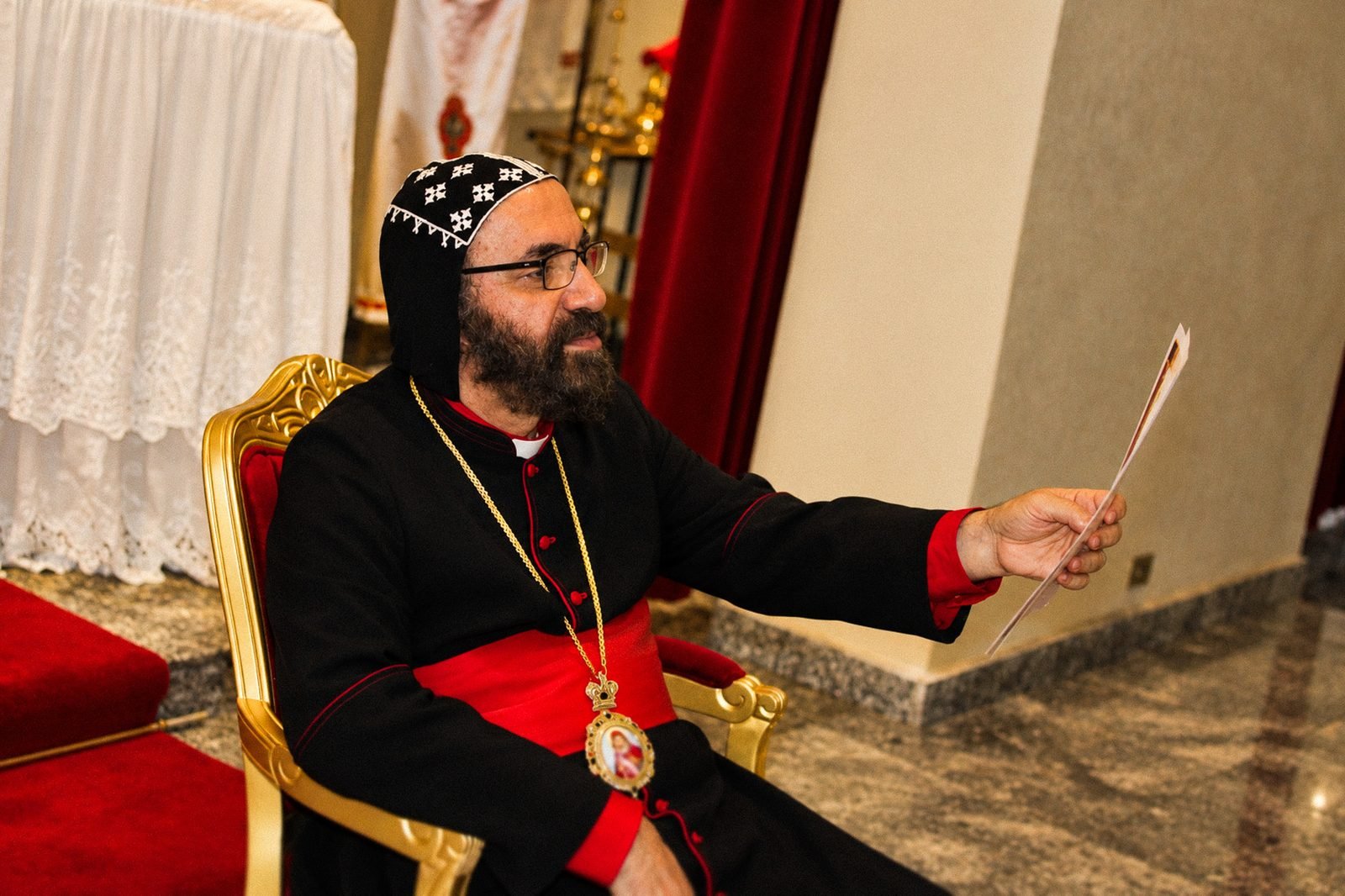 O bispo sentado na cadeira episcopal
